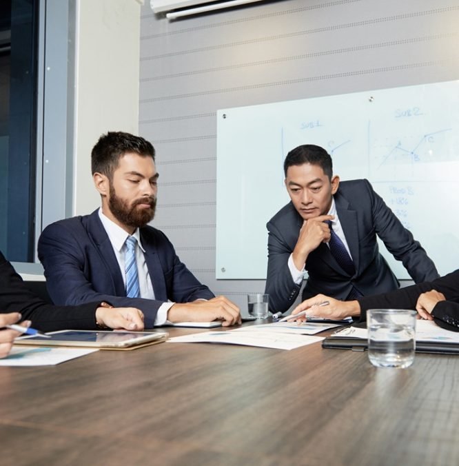 Group of diverse men and women gathering at table in office and having discussion